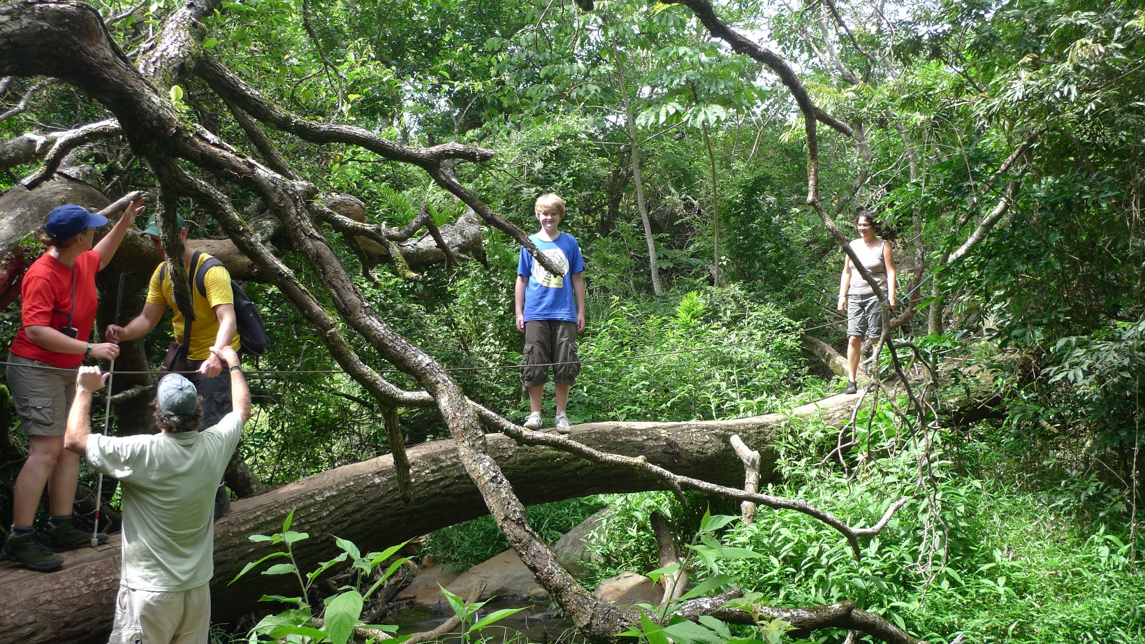David und Christina überqueren einen Fluss über einen Baum